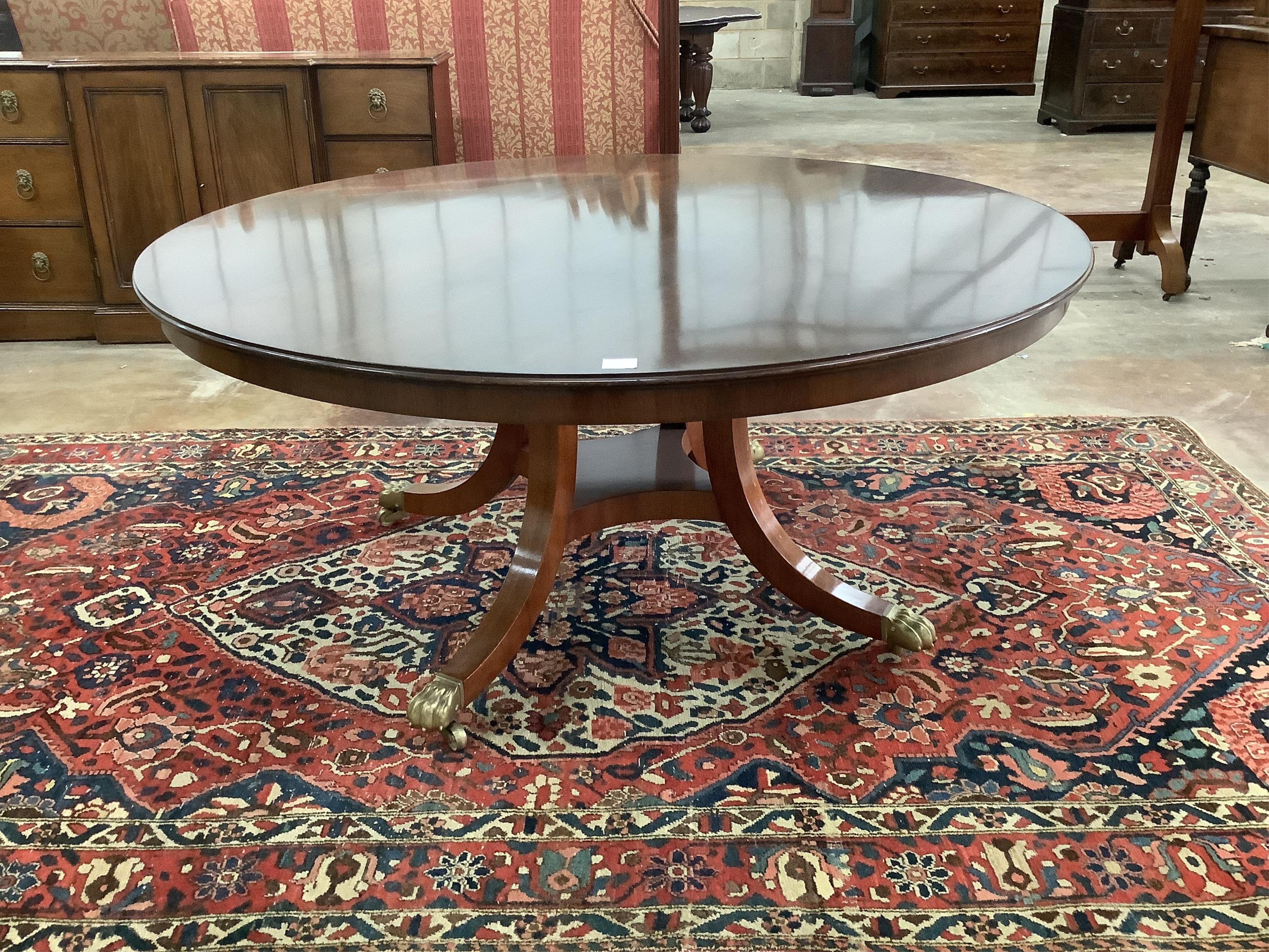 A reproduction George III style mahogany circular segmental extending dining table, diameter 155cm, 230cm extended, height 72cm. Condition - fair